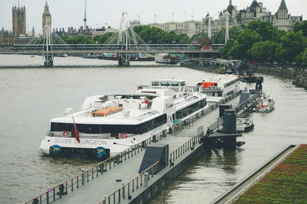 Luxury river cruise ship docked near iconic London landmarks on a quiet day.