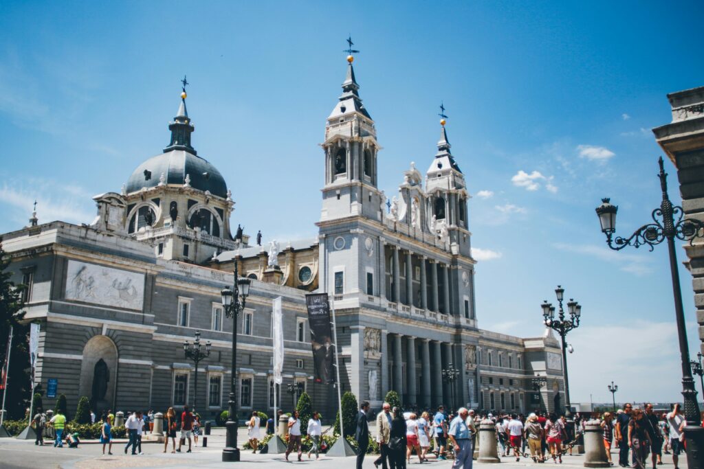 Almudena Cathedral in Madrid with tourists on a bright summer day.