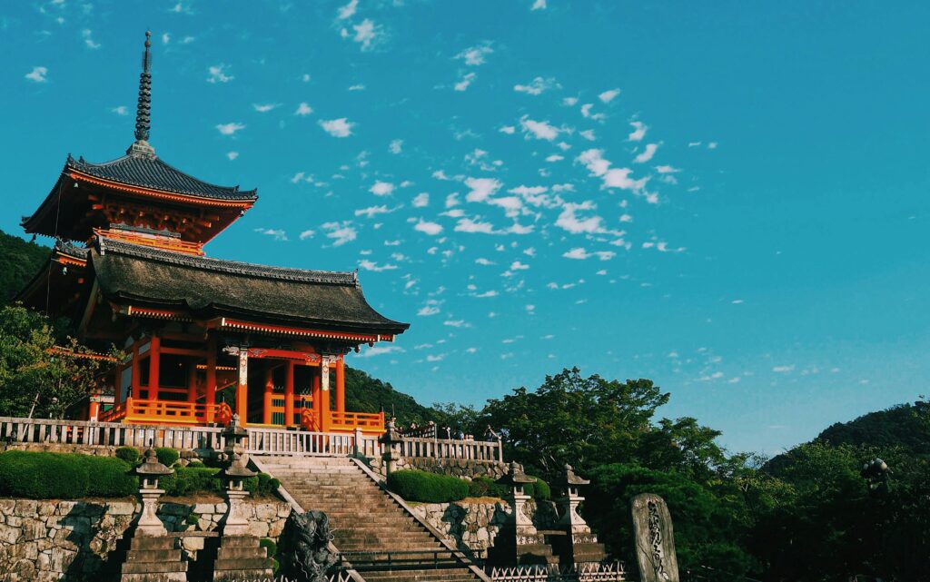Beautiful view of Kiyomizu Dera Temple in Kyoto, showcasing traditional Japanese architecture under a vibrant sky.