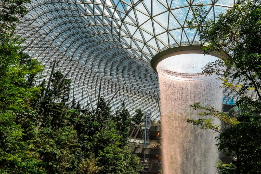 The iconic indoor waterfall at Jewel Changi Airport surrounded by lush gardens.