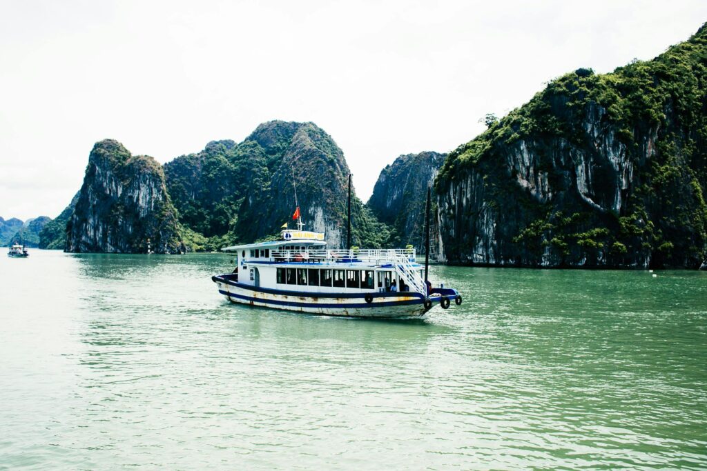 Tranquil waters and limestone cliffs of Halong Bay with a traditional boat.